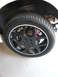 1996 Ford Probe - A close-up view of a car's wheel and tire assembly, showing a black five-spoke rim with a white accent ring.