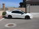 1996 Ford Probe - A white sedan with a prominent rear spoiler and black wheels is parked in front of a garage.