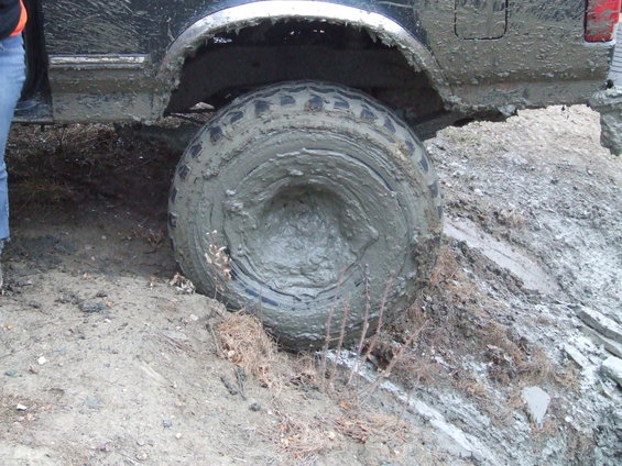 Mud-covered tire stuck deep in mud