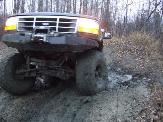 Ford Bronco driving through mud, front view. Winch on bumper