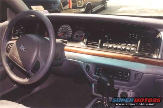 Interior dashboard of a 2002 Ford Crown Victoria with wood trim and Ford logo on steering wheel