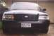2002 Ford Crown Victoria - Front view of a black 2002 Ford Crown Victoria parked in front of a garage.