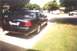 2002 Ford Crown Victoria - A dark blue 2002 Ford Crown Victoria is parked in a driveway, with another vehicle visible behind it.