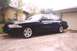 2002 Ford Crown Victoria - A dark sedan is parked in a driveway in front of a garage and a brick house.