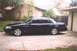 2002 Ford Crown Victoria - A dark blue 2002 Ford Crown Victoria sedan is parked on a concrete driveway in front of a house and garage.