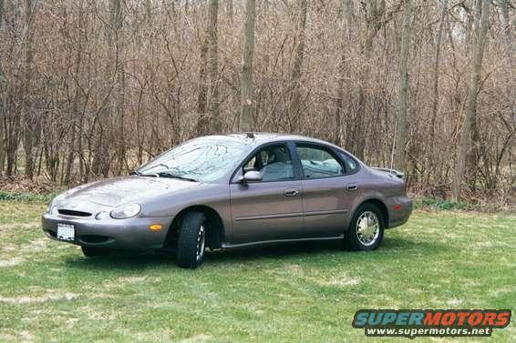 1996 Ford Taurus sedan parked on grass with bare trees in background