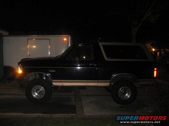 Black SUV parked at night, side view. Looks like a Bronco