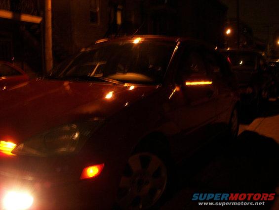 Red 2002 Ford Focus parked at night, front 3/4 view, with illuminated turn signal on side mirror