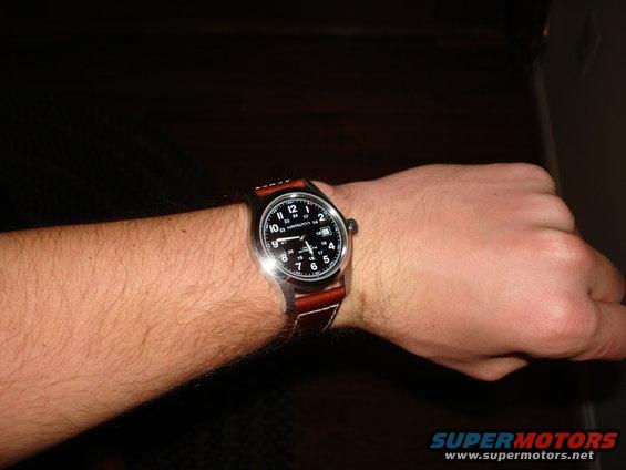 Wrist with a Hamilton watch and brown leather strap