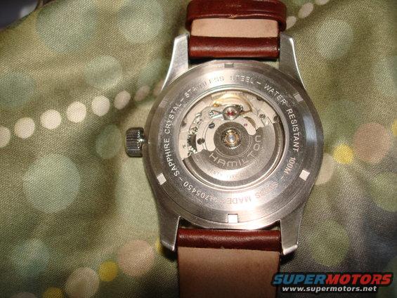 Watch caseback showing automatic movement and Hamilton branding. Brown leather strap visible
