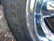 1999 Ford Mustang - A close-up view of a vehicle's tire and chrome wheel, showing details of the tire's tread and sidewall markings.