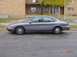 1996 Ford Taurus - A gray 1996 Ford Taurus is parked on the side of a street in front of a brick building.