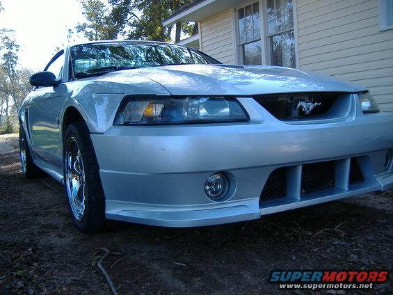 Silver Ford Mustang with chrome wheels, front bumper, and grille with a horse emblem
