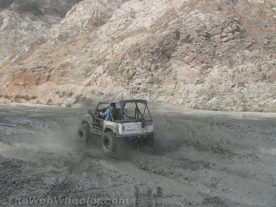 Suzuki Samurai kicking up mud on a dirt road