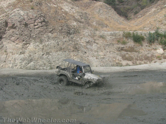 1987 Suzuki Samurai with roll cage stuck in mud, splashing water