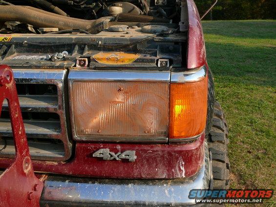 1987 Ford F-Series truck front end with 4x4 badge and damaged headlight