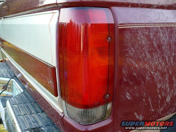 1988 Ford Bronco tail light assembly, red and clear lens, chrome trim. Maroon body panel with white stripe