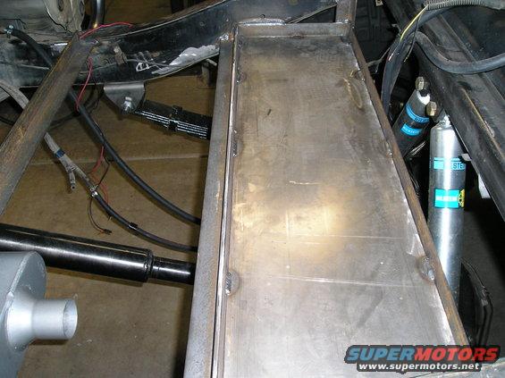 Metal storage box welded onto a vehicle frame with leaf springs and Bilstein shocks visible