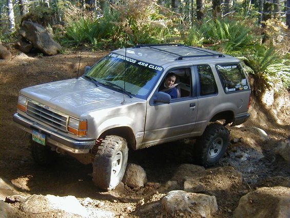 1994 Ford Explorer with lifted suspension and off-road tires navigating a rocky trail