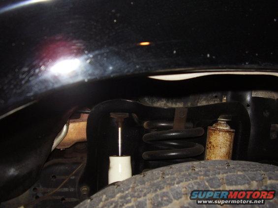 Black vehicle's front suspension with coil spring and shock absorber visible