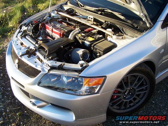 Silver Mitsubishi Lancer Evolution with hood open, showing engine and front wheel
