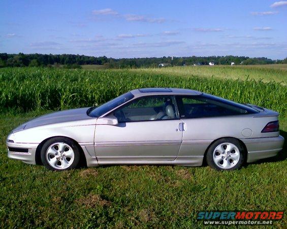 Silver 1990 Ford Probe coupe parked on grass with a cornfield in the background