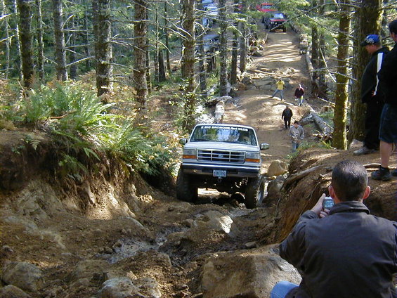 White Ford truck with "BIG BRONCOS 4X4 CLUB" sticker on muddy trail
