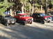 1989 Ford Bronco - Three SUVs are parked in a gravel lot surrounded by trees, with camping tents visible behind them.