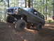 1989 Ford Bronco - This heavily modified Ford Bronco is shown navigating an off-road trail with significant suspension articulation.