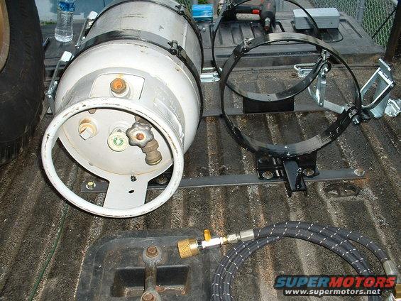 Propane tank with valve and hose assembly, mounted in a truck bed with additional securing rings