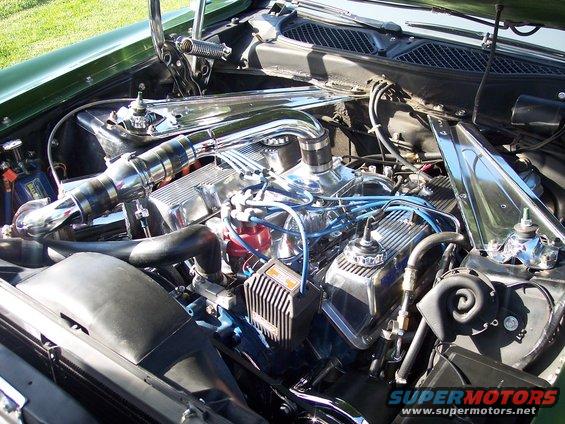 Green 1973 Ford Mustang engine bay with chrome accents and a V8 engine