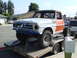 1972 Ford F-100 - A heavily modified pickup truck with a roll cage and off-road tires is transported on a trailer.