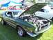 1973 Ford Mustang - A green 1973 Ford Mustang is displayed with its hood up at a car show, revealing the engine bay.