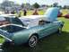 1973 Ford Mustang - A classic teal Ford Mustang convertible is displayed with its trunk and hood open on a grassy field.