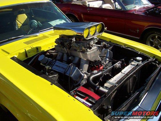 Yellow 1973 Ford Mustang engine with chrome scoop and dual carburetors