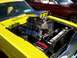 1973 Ford Mustang - The engine bay of a yellow 1973 Ford Mustang features a prominent chrome scoop and dual carburetors, with another classic car visible in th…