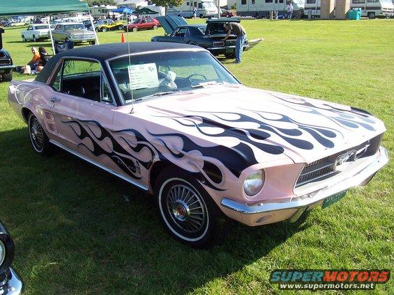Pink 1967 Ford Mustang coupe with black flame graphics on hood and sides, black vinyl roof