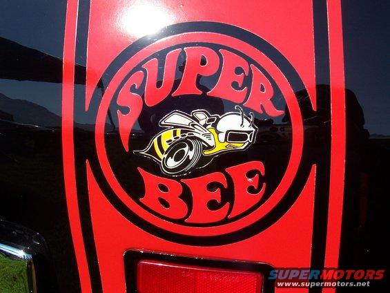 Black car with red and yellow Super Bee decal on the side. Supermotors.net watermark visible
