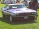 1973 Ford Mustang - A purple 1970 Dodge Challenger is displayed at a car show with other vehicles present.