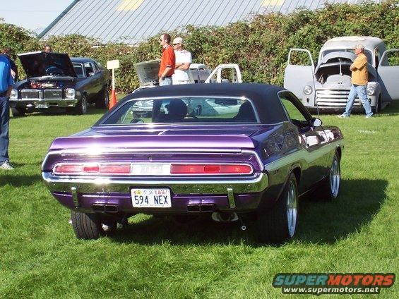 Purple 1970 Dodge Challenger with black vinyl top, rear view. License plate 594 NEX. Other cars and people in background