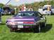1973 Ford Mustang - A purple 1970 Dodge Challenger is parked on grass with other vehicles and people around it.