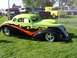 1973 Ford Mustang - Custom hot rod with flames parked on grass, with other vehicles in the background.