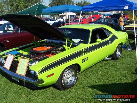 Lime green 1970 Dodge Challenger T/A with black stripes, hood open, parked on grass