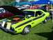 1973 Ford Mustang - A lime green 1970 Dodge Challenger T/A is displayed with its hood open at an outdoor car show.