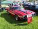 1973 Ford Mustang - A red 1970 Shelby Mustang GT500 is displayed at a car show with other vehicles in the background.