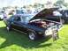 1973 Ford Mustang - A black Dodge Challenger R/T is displayed with its hood open at an outdoor car show.