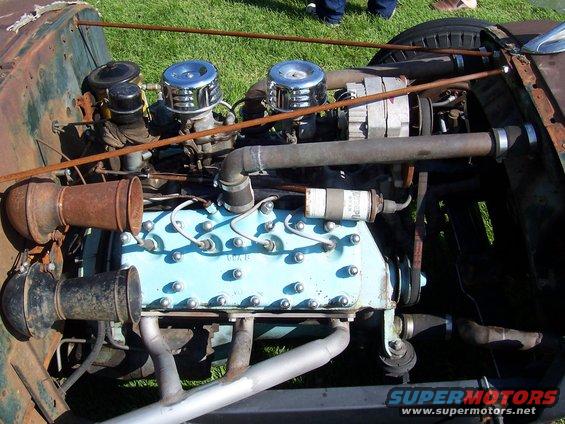 Close-up of an old inline-six engine with dual carburetors and chrome air cleaners