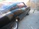 1971 Mercury Cyclone - The rear quarter panel and side of a black coupe are visible, parked next to a wooden fence.