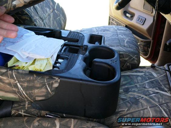 Center console with cup holders and storage compartment, covered in camouflage seat covers