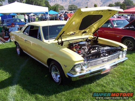 Yellow 1966 Chevrolet Chevelle coupe with hood open, showing engine. Chrome bumper, aftermarket wheels